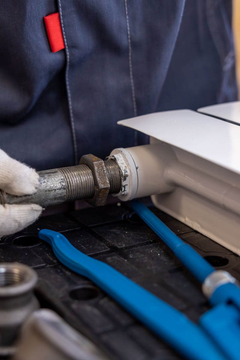 Close-up of a plumber installing a radiator pipe using specialized tools.